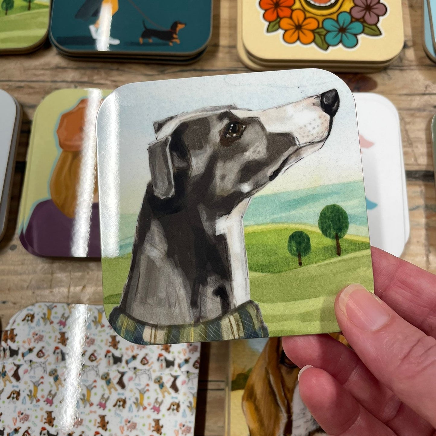 Hand holding a card with a dog illustration among other animal-themed cards on a wooden surface.