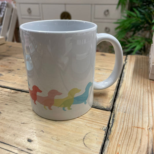 White mug with colorful dachshund design on a wooden surface