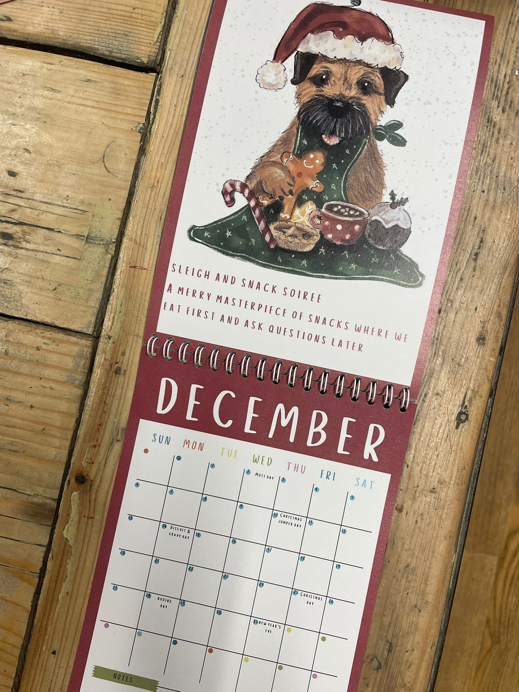 Calendar with a dog wearing a Santa hat on a wooden surface