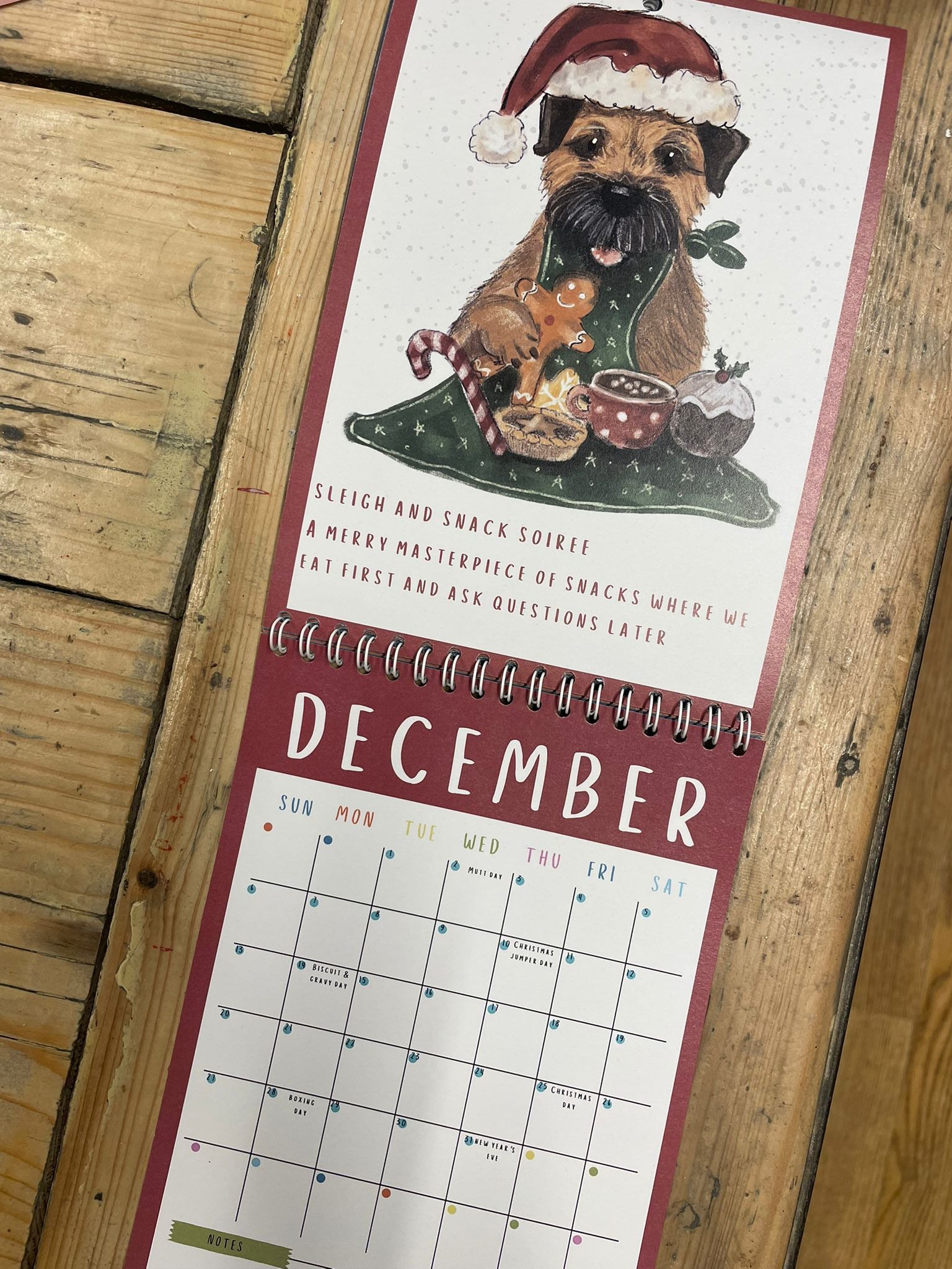 Calendar with a dog wearing a Santa hat on a wooden surface